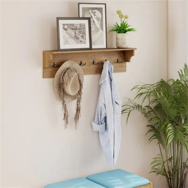 Natural wood wall-mounted coat rack with 6 black hooks and a storage shelf, holding a hat and shirt.
