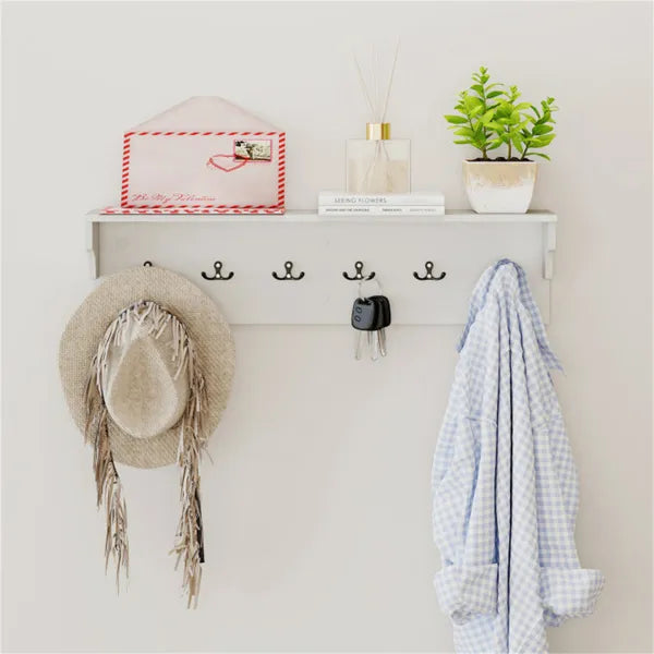 White entryway shelf with six black hooks, a straw hat, keys, a blue shirt, and decor.
