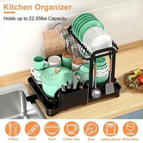 Black 2-tier dish drying rack with mint green dishes, glasses, and utensils on a wooden counter.