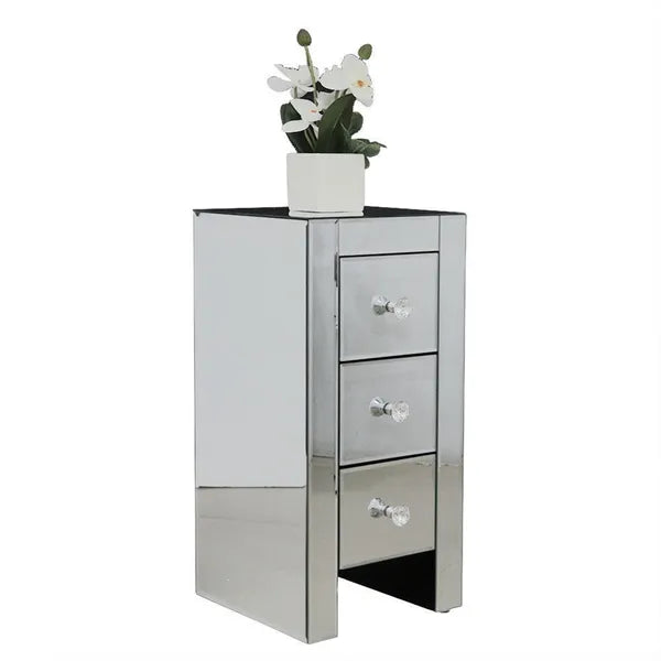 Mirrored compact end table with three drawers and crystal knobs, topped with a white orchid plant.