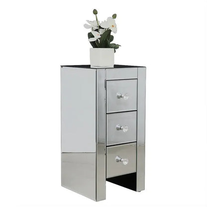Mirrored compact end table with three drawers and crystal knobs, topped with a white orchid plant.
