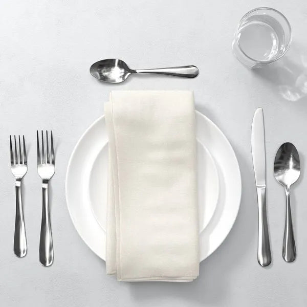 Modern 20-piece mirror-polished stainless steel silverware set with white plate, napkin, and glass.
