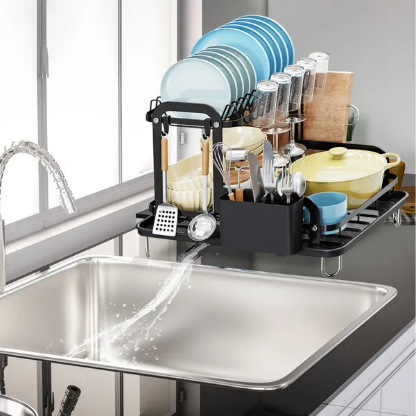 Black 2-tier dish drying rack with drainboard, holding plates, glasses, utensils, and a pot above a sink.