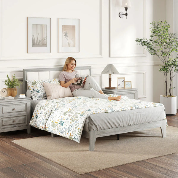 Modern full-size bed frame with light gray wood and white upholstered headboard, supporting a floral duvet.