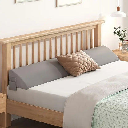 Gray ergonomic mattress gap filler with side pocket on a wooden bed, preventing items from falling.