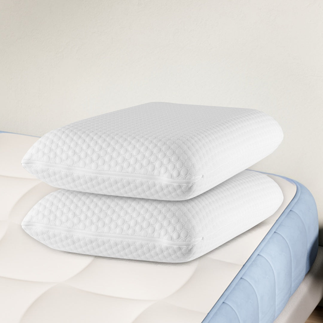 Two white orthopedic memory foam pillows with textured covers, stacked on a mattress.