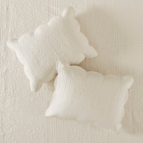 Cream reversible scalloped edge quilt set with two decorative quilted pillows.