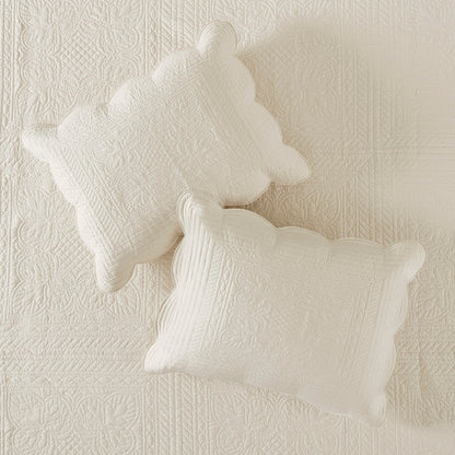 Cream reversible scalloped edge quilt set with two decorative quilted pillows.