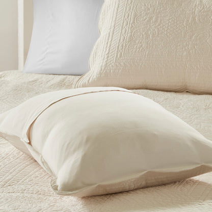 Cream reversible scalloped edge quilt set with quilted texture and solid pillow shams.