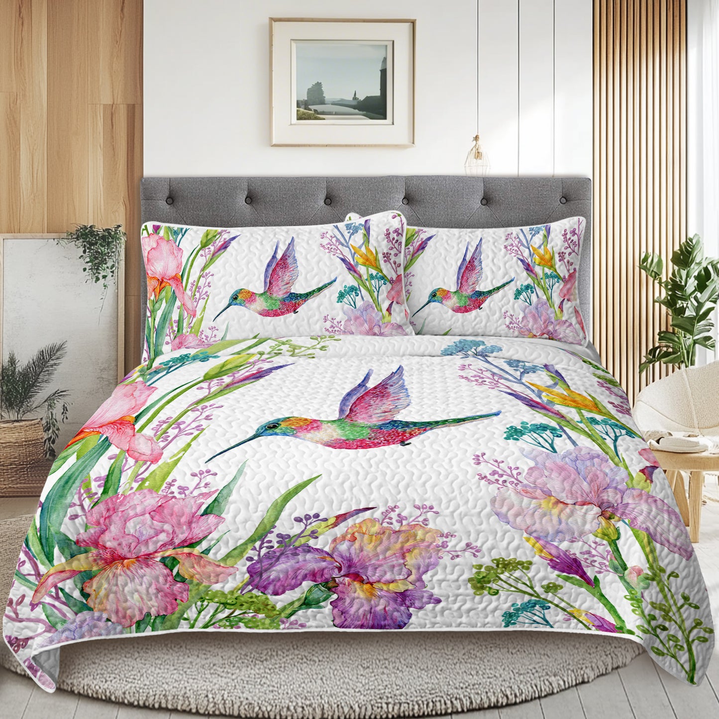 White watercolor hummingbird and floral quilt set with matching shams on a bed in a modern bedroom.