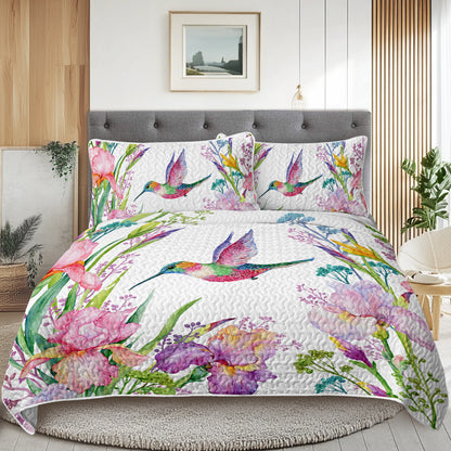White watercolor hummingbird and floral quilt set with matching shams on a bed in a modern bedroom.