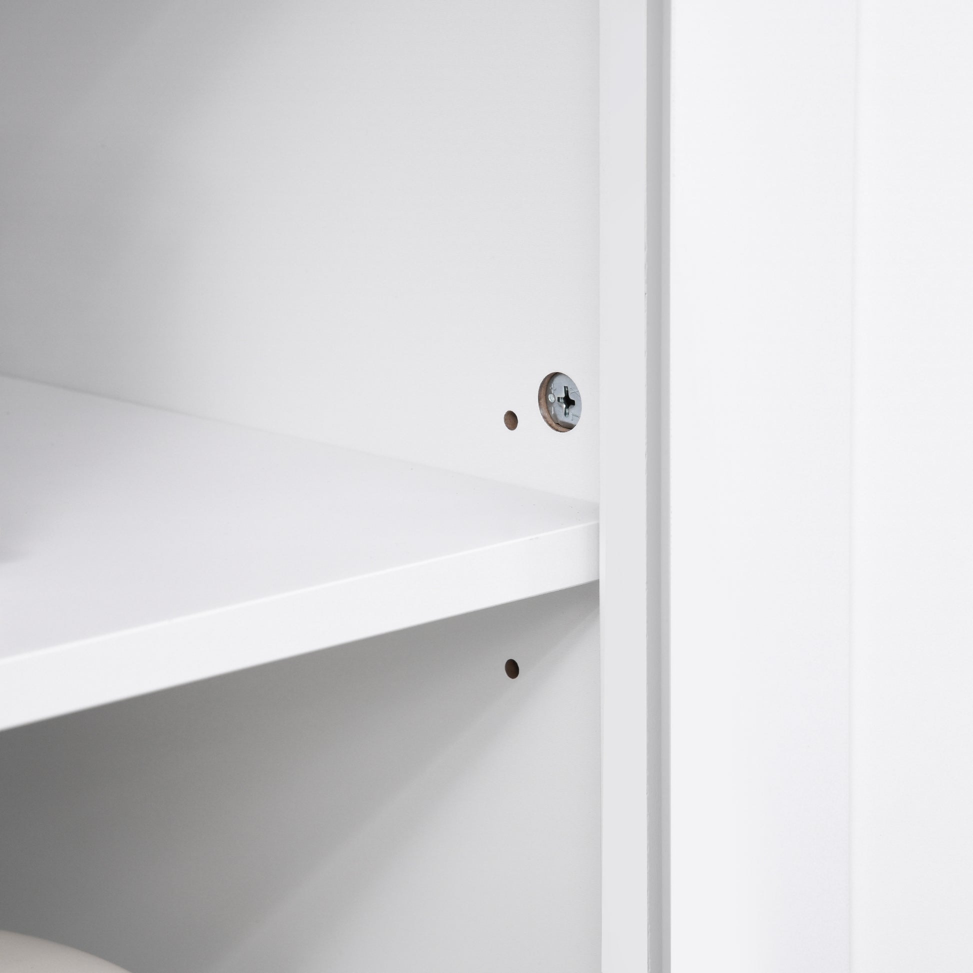 Close-up of a white MDF cabinet interior with adjustable shelves and visible screw hardware.