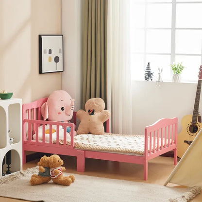 Pink wooden toddler bed with vertical plank headboard, side rails, and low design in a child's room.