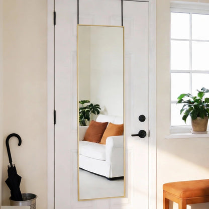 Gold-framed full-length mirror hanging over a white door, reflecting a living room.