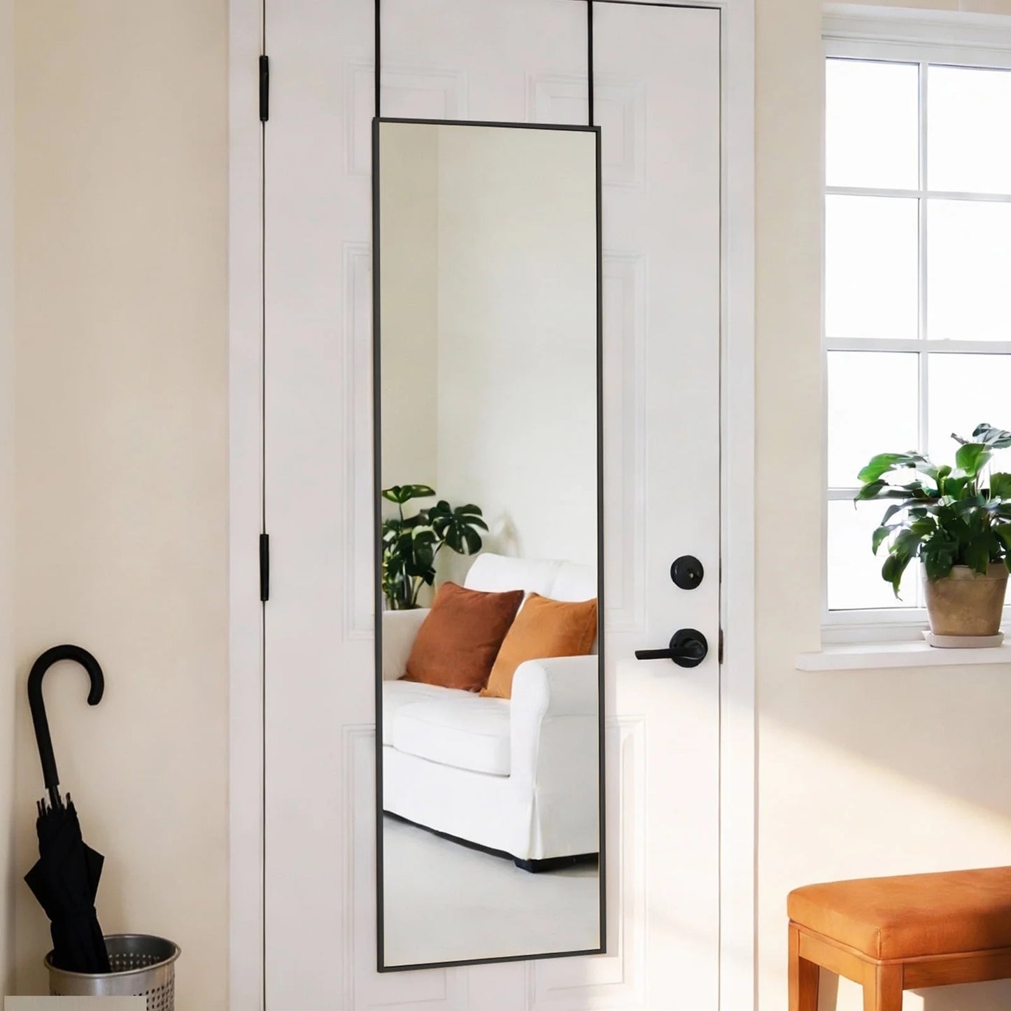Full-length minimalist mirror with a slim black aluminum frame, hanging over a white door.