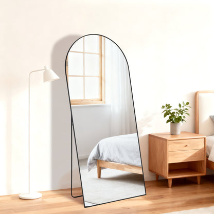 Black arched full-length standing mirror, 21x56 inch, with a sleek metal frame in a modern bedroom.