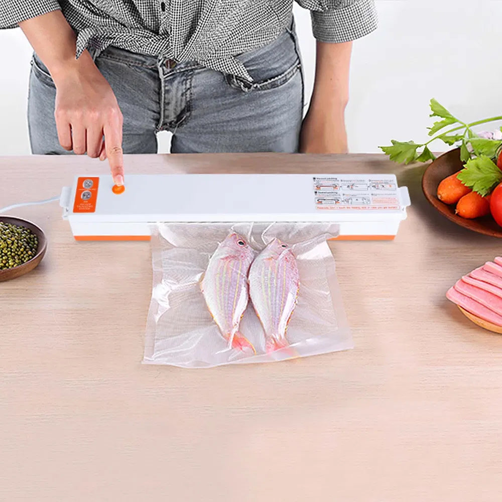 White and orange automatic vacuum sealer preserving two fish in a bag on a wooden table.