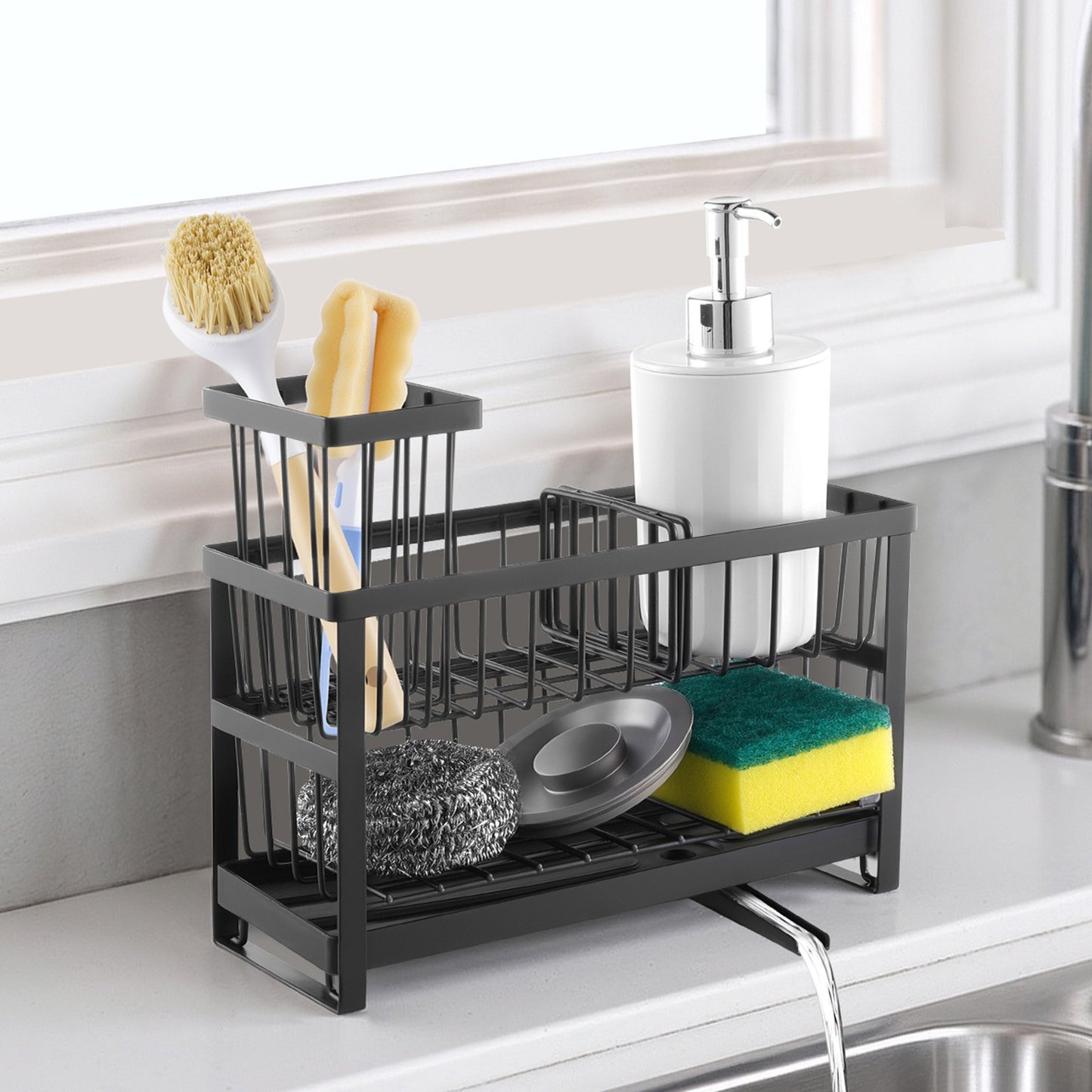 Black metal sink caddy with compartments for sponges, brush, and soap dispenser, draining into a sink.