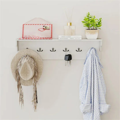 White entryway shelf with six black hooks, a straw hat, keys, a blue shirt, and decor.